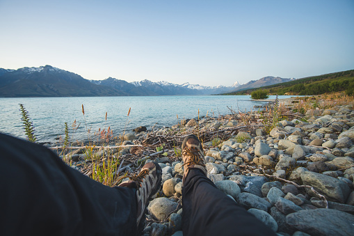 POV of a hiker sitting and relaxing at pebbles beach and enjoying landscape scenery.