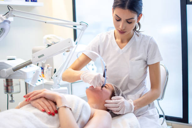 young woman receiving hydra-facial therapy at beauty salon - hydrafacial stockfoto's en -beelden