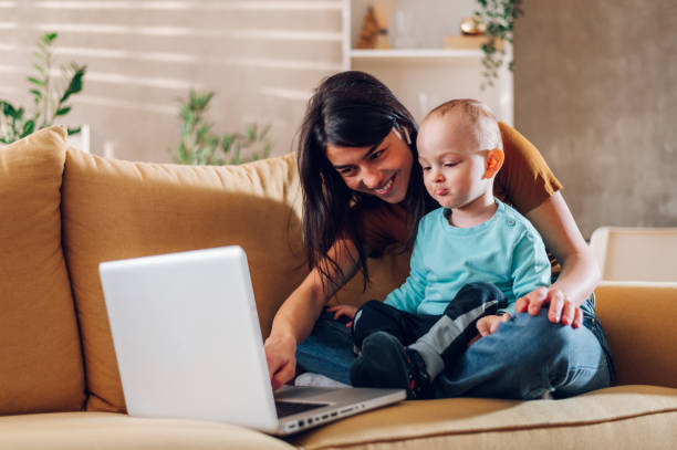 istock Mother playing and hugging with her child son while using laptop at home 1457487678