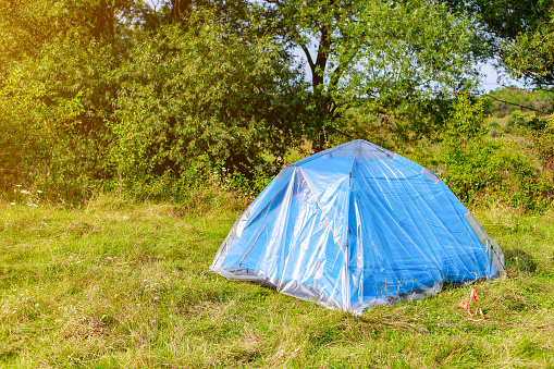 blue tent of a tourist in nature is covered with oilcloth or polyethylene film. Protection from getting wet. Background