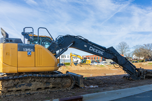 Pineville, NC, USA-15 January 2023: Construction site in downtown with two backhoe tractors. Sunny, blue sky day.