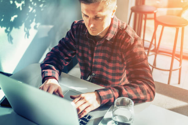 istock Cheerful freelancer using laptop sitting at table in cafe in sunny day 1457489298