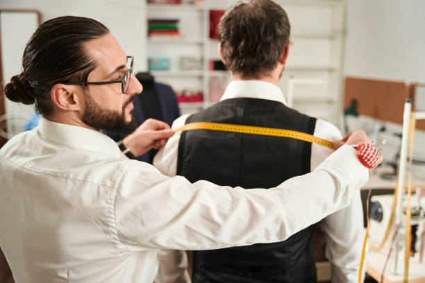 istock Focused couturier taking customer body measurements using tape measure 1457491040