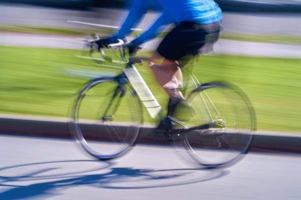Cyclists in colorful outfits riding fast through city during large urban bike event with artistic motion blur. Vertical sport background. Concept of motion, sport and community