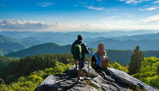 Man and woman on top of the mountain enjoying beautiful scenery. People relaxing in the mountains. Near Asheville, North Carolina. Blue Ridge Parkway.USA.