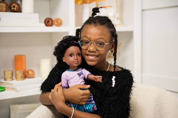 Portrait of black little girl with same skin colour doll. stock photo