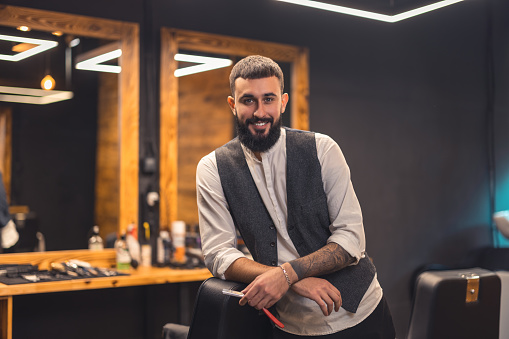 Stylish barber. Dark-haired bearded man in a stylish outfit