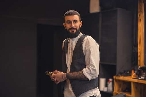 Barber. Stylish bearded young man in a barbershop