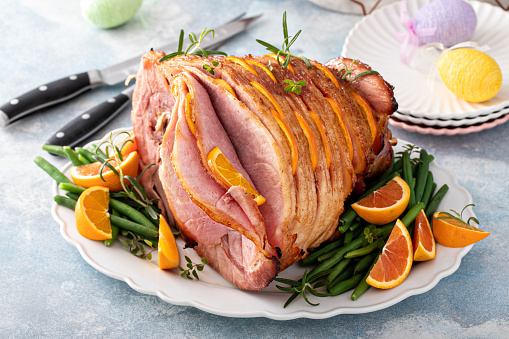 Easter ham stuffed with orange slices and herbs, spiral sliced glazed ham