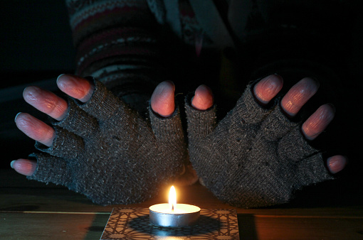 Person warming their hands over a candle.
