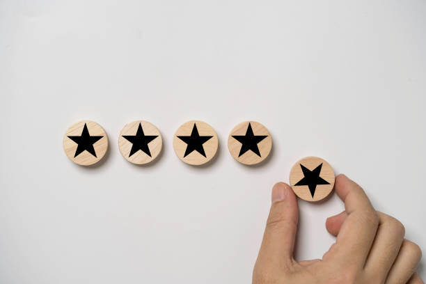 istock Hand holding black star which print screen on round wooden to give five stars for excellent evaluate after customer use product service , ISO and quality standard certificate concept. 1457504126