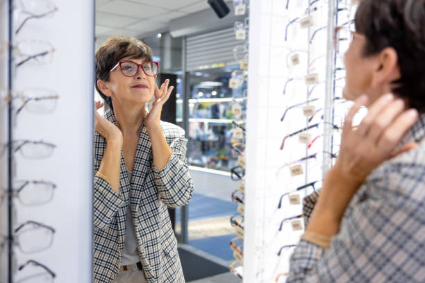 istock Mid aged good-looking lady trying on eyeglasses at the optical store 1457510663