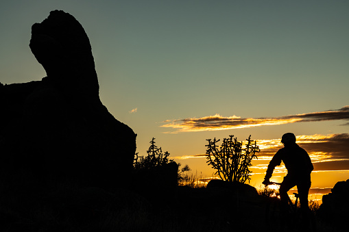 a man in silhouette makes his way across the landscape at sunset while riding his mountain biking.  such beautiful nature scenery and adventure and exercise opportunities abound in central new mexico.