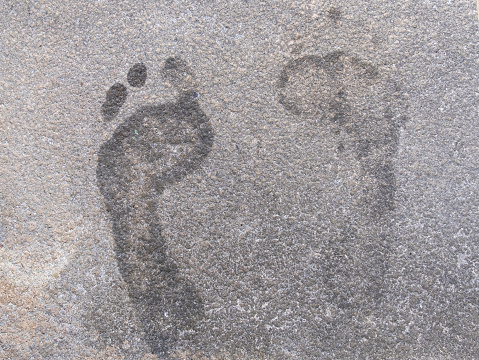Wet human footprints on concrete pavement tile background texture