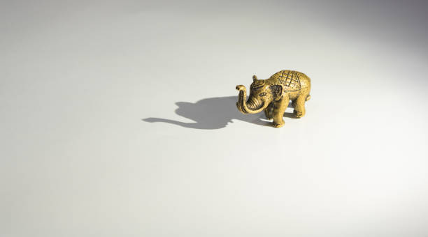 brass elephant and shadow small brass elephant with its big shadow elephant figurine stock pictures, royalty-free photos & images