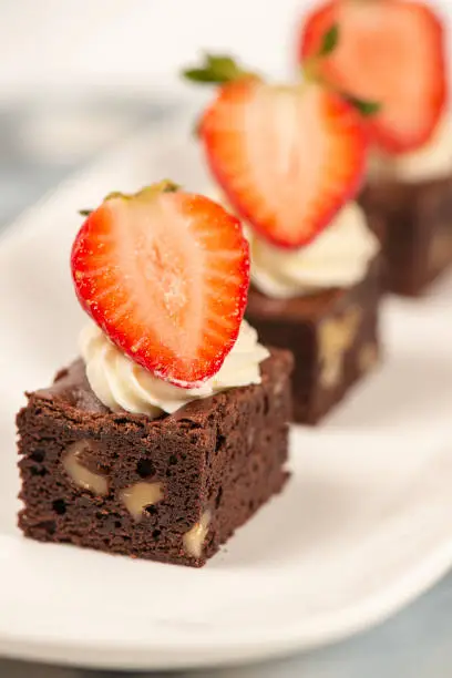 Deliciously rich cake brownie slice with Chantilly cream and fresh strawberry.