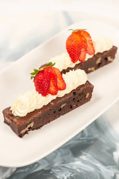 Deliciously rich cake brownie slice with Chantilly cream and fresh strawberry.