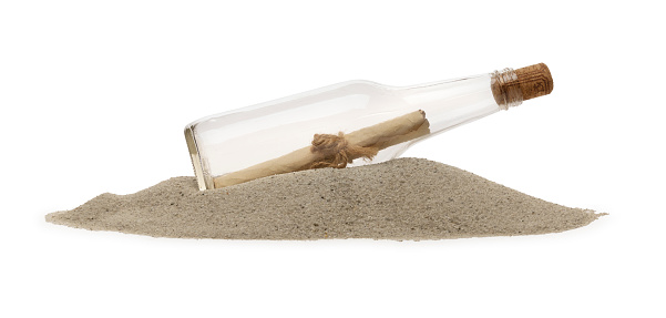 This is a side view close up color photograph of a Message in a Bottle on Sand dune isolated on a white background