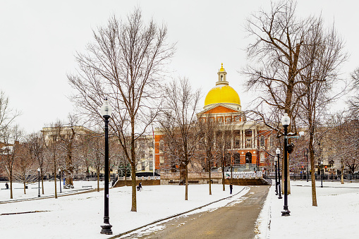 Boston, Massachusetts, USA - January 16, 2023: View across a snow covered Boston Common of the Massachusetts State House. The State House is the state capitol and seat of government for the Commonwealth of Massachusetts.