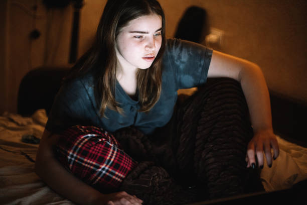 istock Young female teenage student using laptop computer while studying at home at night 1457538495