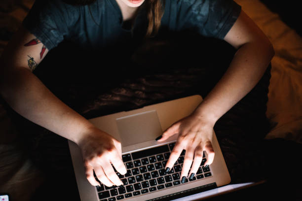 istock Young woman using laptop computer while sitting in bed at home at night 1457538589