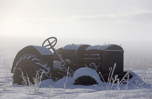 An old tractor on an abandoned farm in winter.