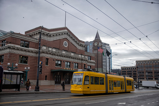 Street view of downtown Seattle, WA, USA on a winter afternoon. A yellow street car seen in front of Union Station in the international district.