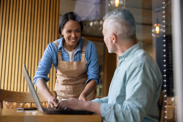 istock Friendly waitress serving a coffee to a man working at a cafe 1457546969