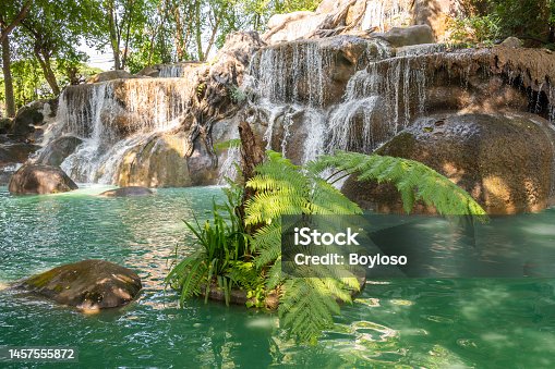 istock Water flowing from large artificial waterfall in ornamental garden. 1457555872