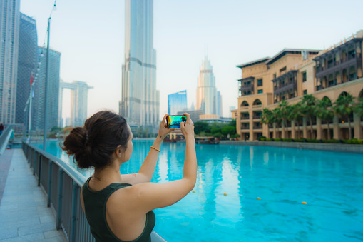 Young Caucasian woman photographing with smartphone near the Dubai fountain