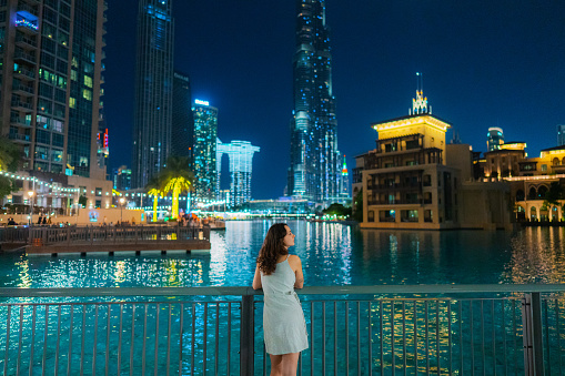 Young Caucasian woman walking in Dubai near Burj Khalifa and Dubai fountain at night