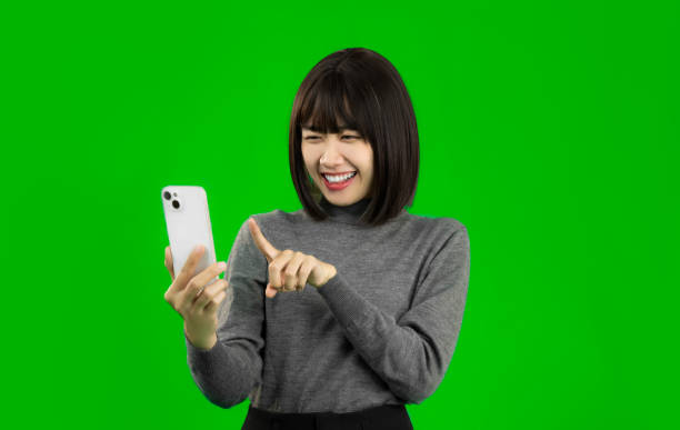 istock Happy Asian woman using a smartphone in hand isolated green screen. technology IoT, internet of things concept. 1457562434