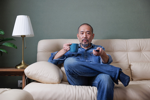 Middle-aged man sitting on the sofa watching TV