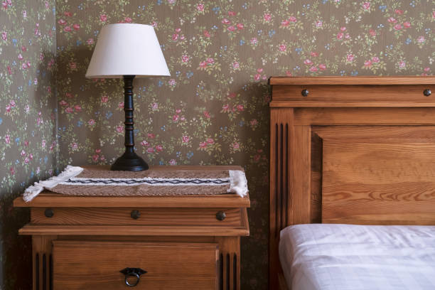 detal wystroju luksusowego pokoju hotelowego z drewnianym łóżkiem i stolikiem nocnym. tapeta z kwiatowym nadrukiem - bed and breakfast inn lamp bed zdjęcia i obrazy z banku zdjęć