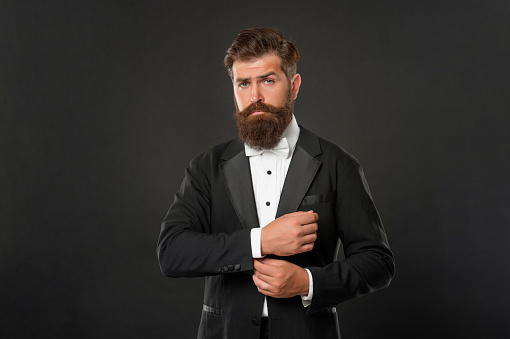 elegant butler in tuxedo on black background, suit.