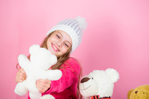 Why kids love stuffed animals. Toy every child dreaming. Kid little girl play with soft toy teddy bear on pink background. Happy childhood concept. Child small girl playful hold teddy bear plush toy.