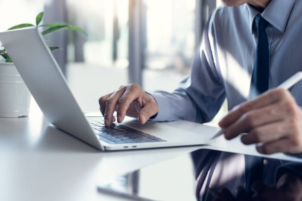 istock Businessman working on laptop computer, surfing the internet and analyzing business report with digital tablet pc on office table. 1457585436