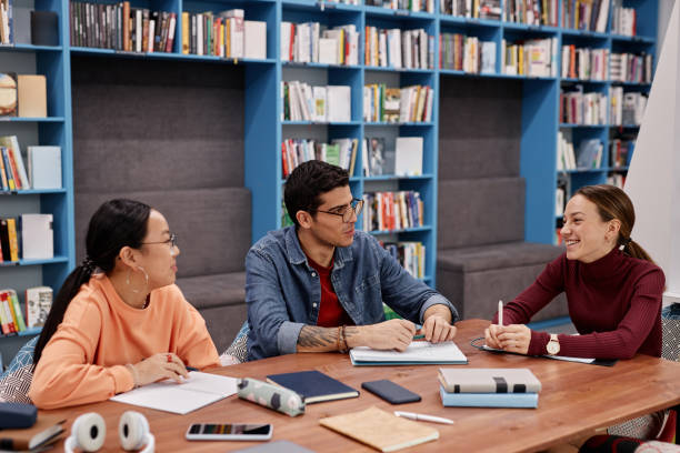 istock Group of three young people studying together in modern college library 1457587239