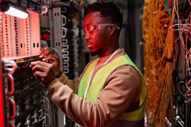 Network technician inspecting servers in data center red neon light Side view portrait of network technician inspecting servers in data center lit by red neon light sound technician stock pictures, royalty-free photos & images