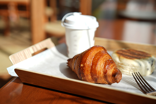 Close-Up Of Coffee Cup And Croissants On Serving Tray With Morning Sun