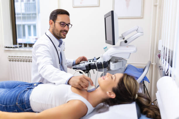 Man endocrinologist making ultrasonography to a female patient in an ultrasound office. Ultrasound diagnostics of the thyroid gland. Man endocrinologist making ultrasonography to a female patient in an ultrasound office. Ultrasound diagnostics of the thyroid gland. thyroid disease stock pictures, royalty-free photos & images