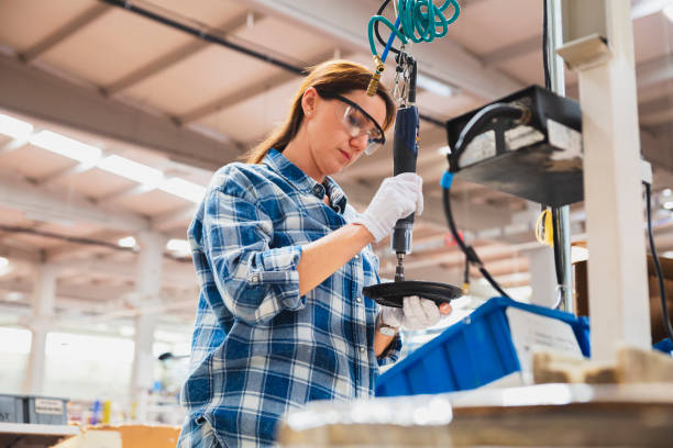 istock Female industrial worker using air impact wrenches at factory 1457592444