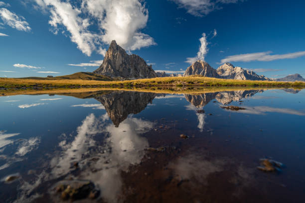 Mountain peaks and clouds reflecting in lake high up in the dolomite mountains on sunny day
