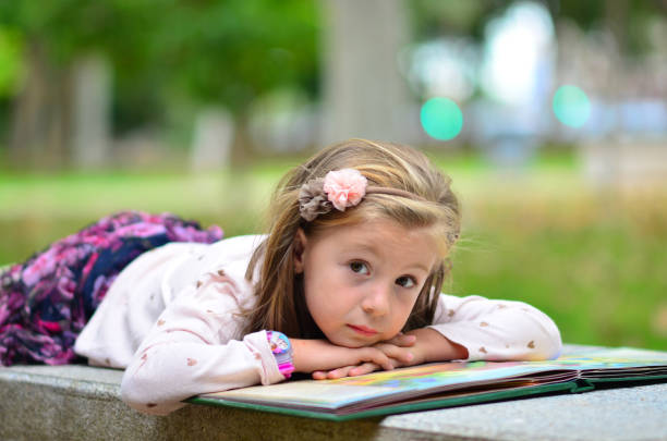 Girl with a book in the park lie on a bench