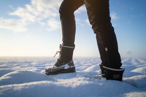 Side view legs of woman walking through snow