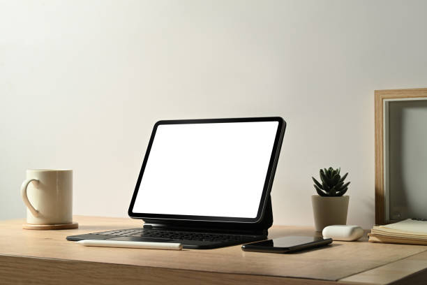 istock Digital tablet, picture frame, coffee cup and houseplant on wooden table. Minimal workplace, Blank screen for your advertise. 1457596043