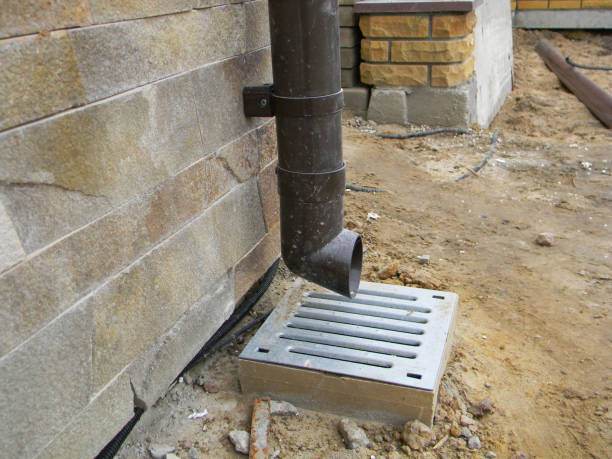 istock Close up on rain gutter downspout pipe with drain hole on house construction site. Gutter drain construction. Underground gutter drainage close up. 1457597328