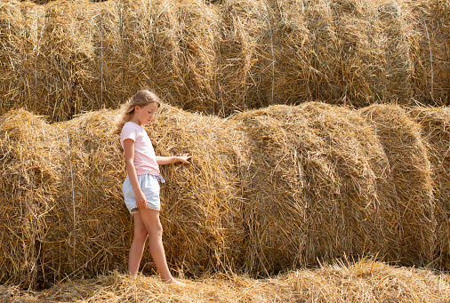 girl with blonde long hair go near haystacks, nature backgrounds, summertime