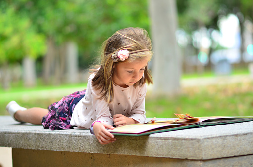 Girl with a book in the park lie on a bench