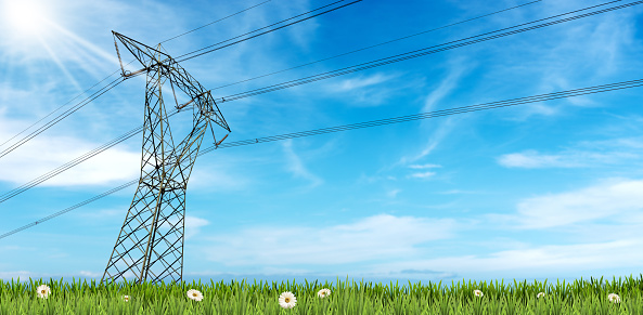 Photography of a high voltage tower on a green meadow, power line with electric cables and insulators against a beautiful blue sky with clouds, sunbeams and copy space.
